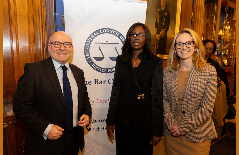 A photo of three people in front of a Bar Council banner