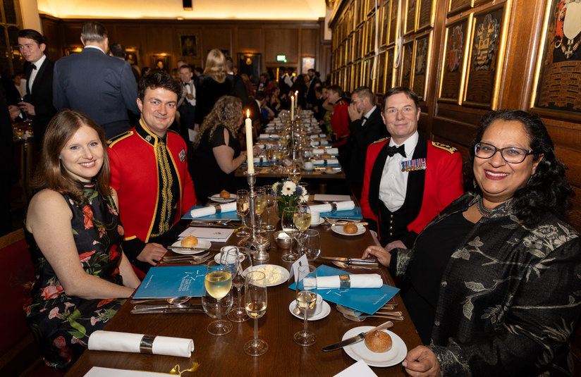 A photo of people facing the camera sitting at a long dinner table with place settings