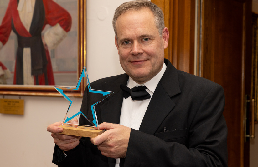 A photo of Daniel Lee with the award won by the Government Legal Department’s Windsor Framework Team