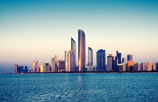 A photo of the Abu Dhabi skyline at sunset with water in the foreground