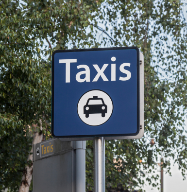 A photo of a sign with 'Taxis' written on it and a symbol of a taxi