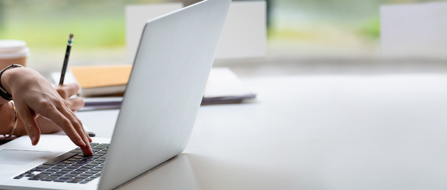 Photo of a person at a laptop at a window