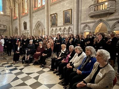 Women seated and standing listening to a speech in the Royal Courts of Justice Great Hall