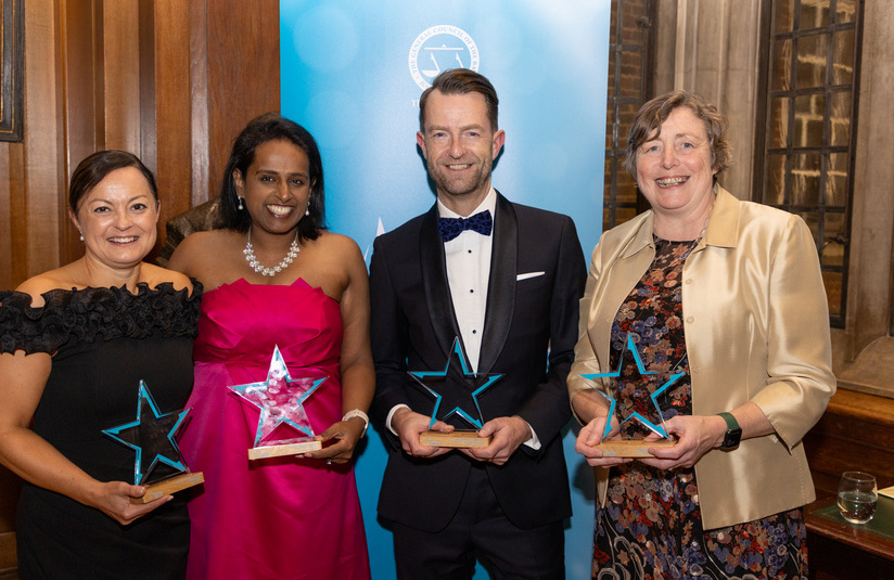 A photo of 4 people standing and holding awards