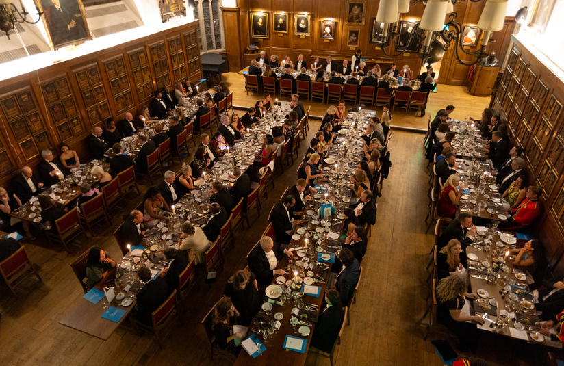 A photo taken from above looking down and across at 5 dinner tables filled with people sitting and talking 