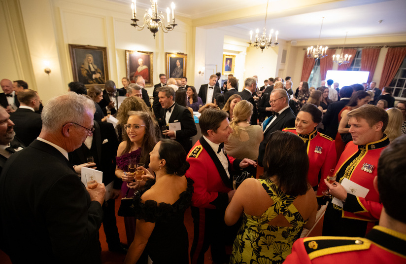 A wide photo of about 30 to 50 people standing and talking 