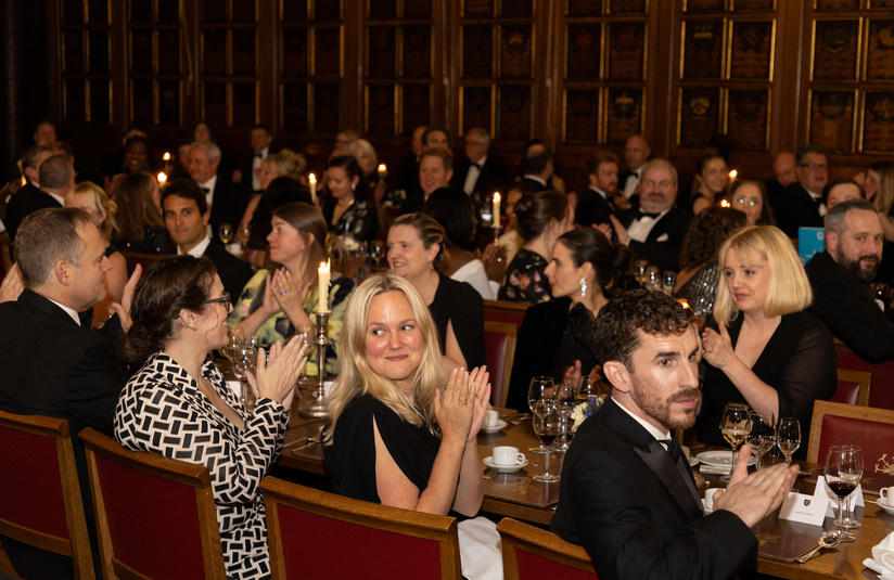 A photo of people seated at dinner tables clapping