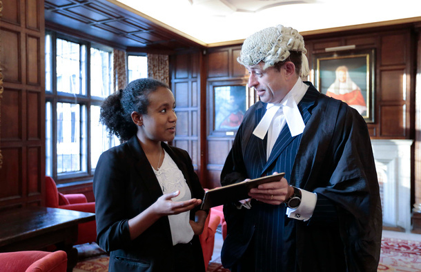 Woman talking to a barrister in wig and gown.