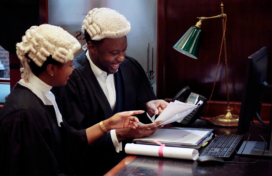 Two barristers talking while holding some papers.