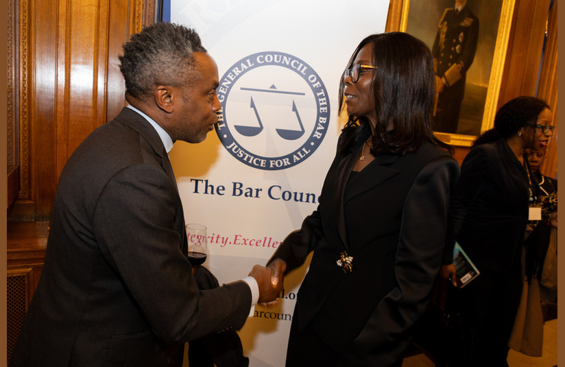 A photo of two people shaking hands in front of a Bar Council banner