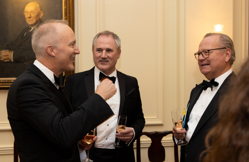 A photo of three people standing and talking jovially