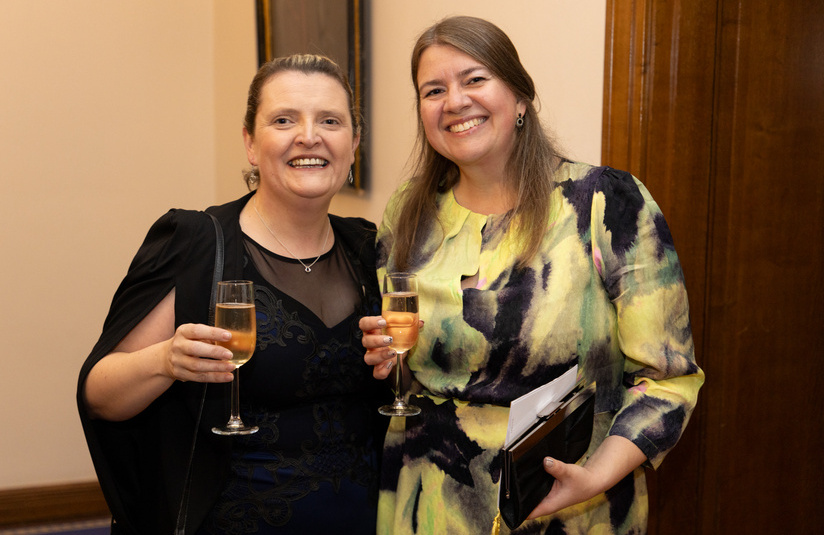 A photo of two people smiling at the camera, holding champagne