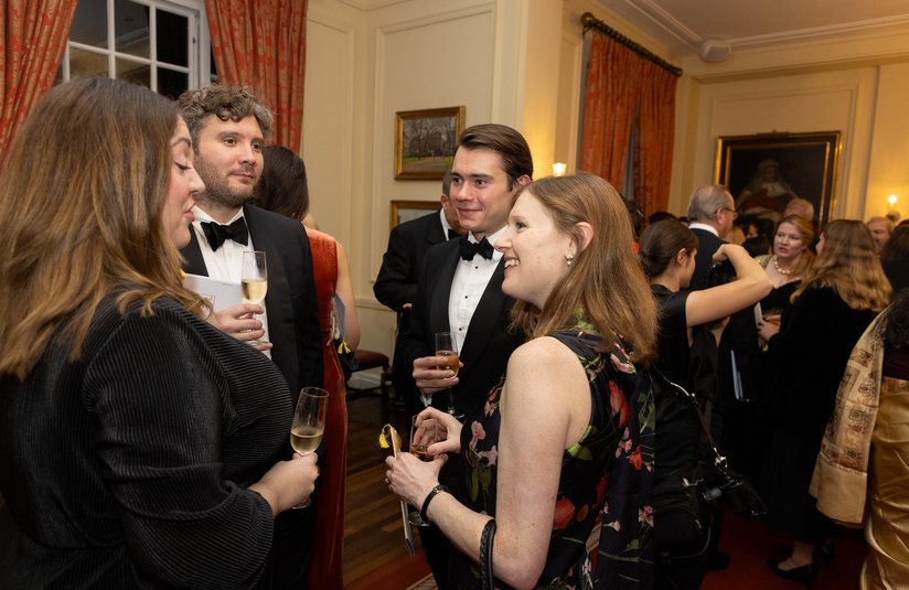 A photo of people standing in groups and talking